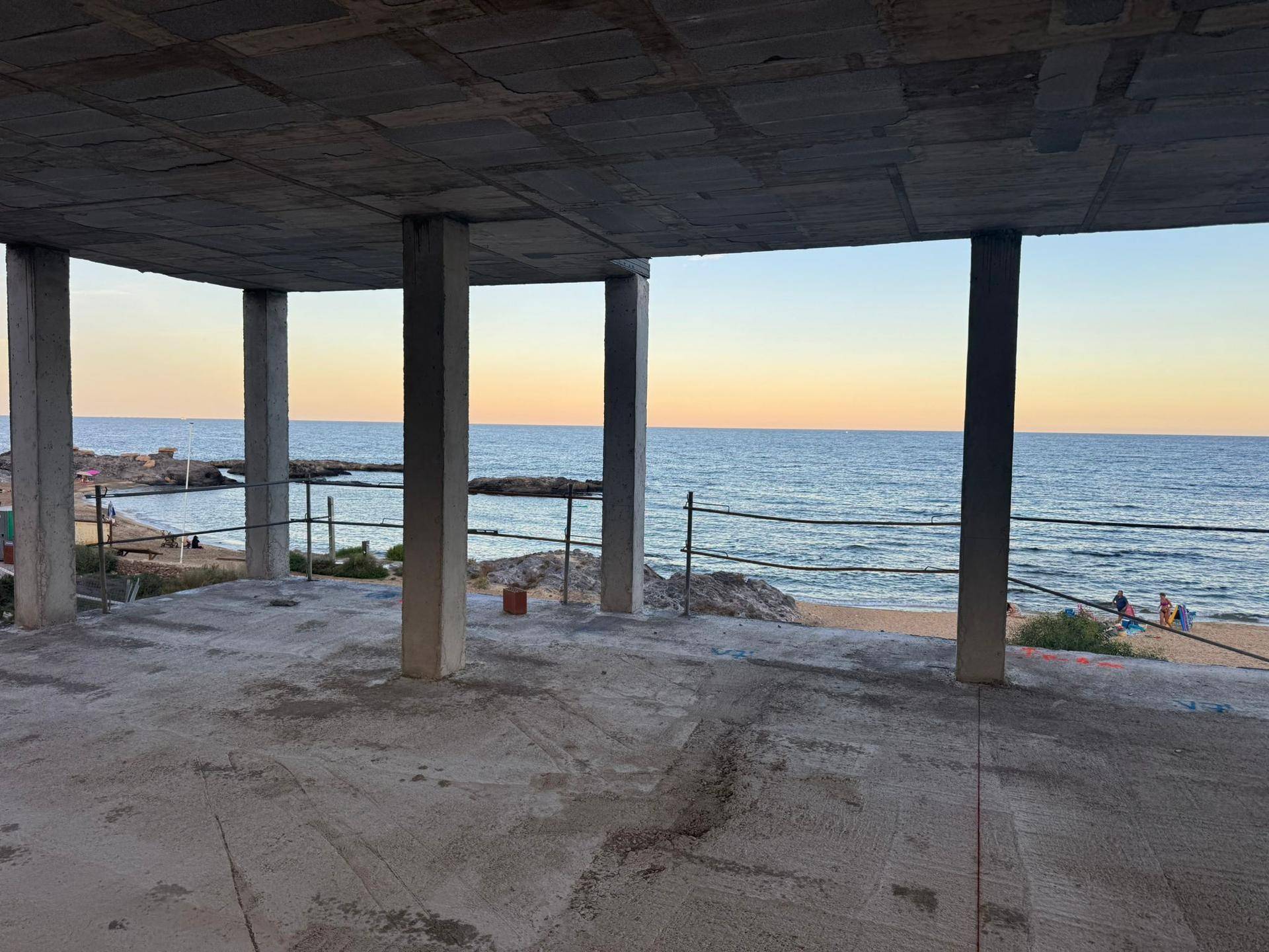 Innenansicht der Baustelle mit Blick auf das Meer, zeigt die Betonstruktur und den Rohbau.