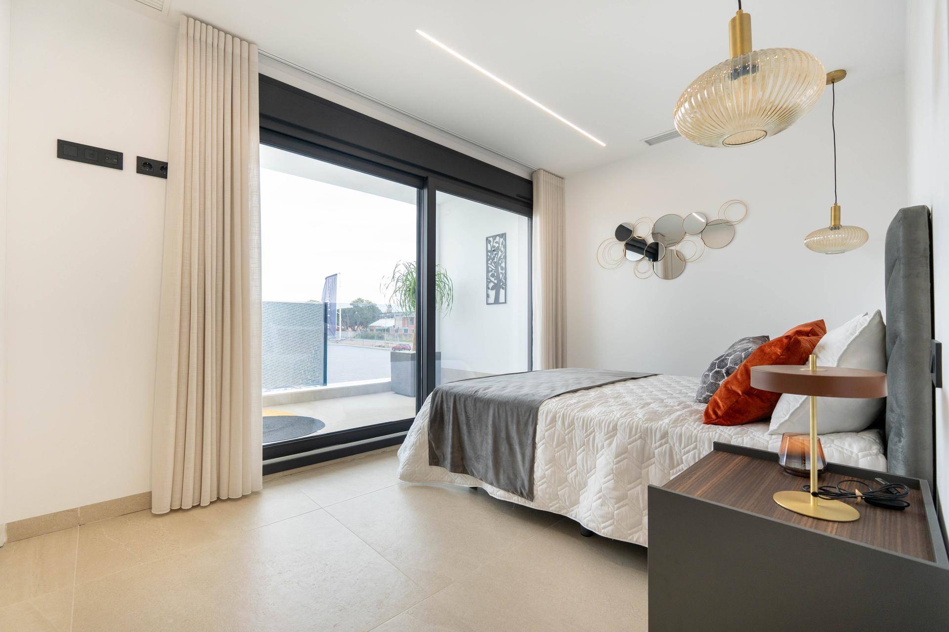 Lichtdurchflutetes Schlafzimmer mit großen Fenstern und Zugang zu einem privaten Balkon.