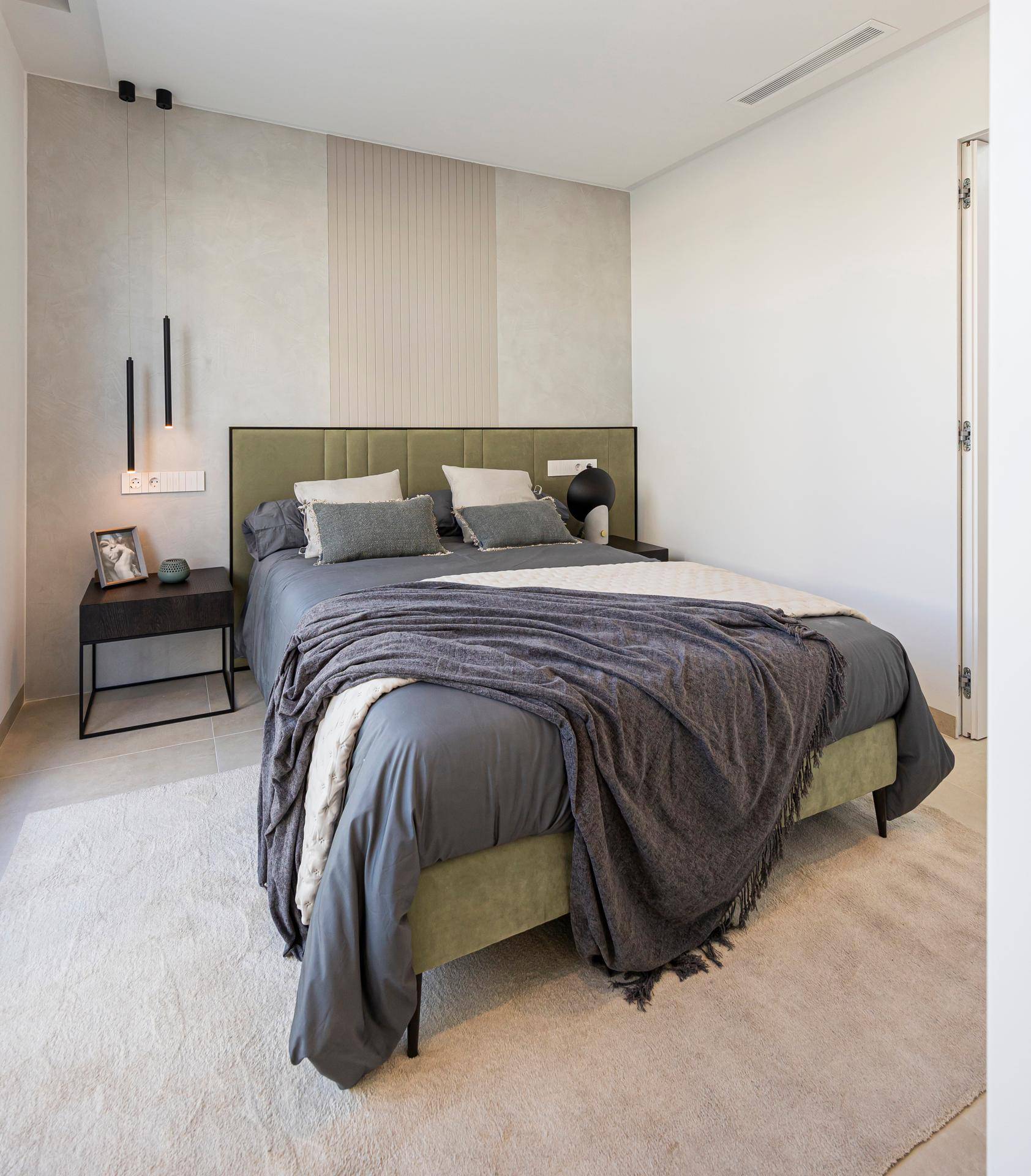 Helles Schlafzimmer mit modernem Bett, Nachttisch und indirekter Beleuchtung.