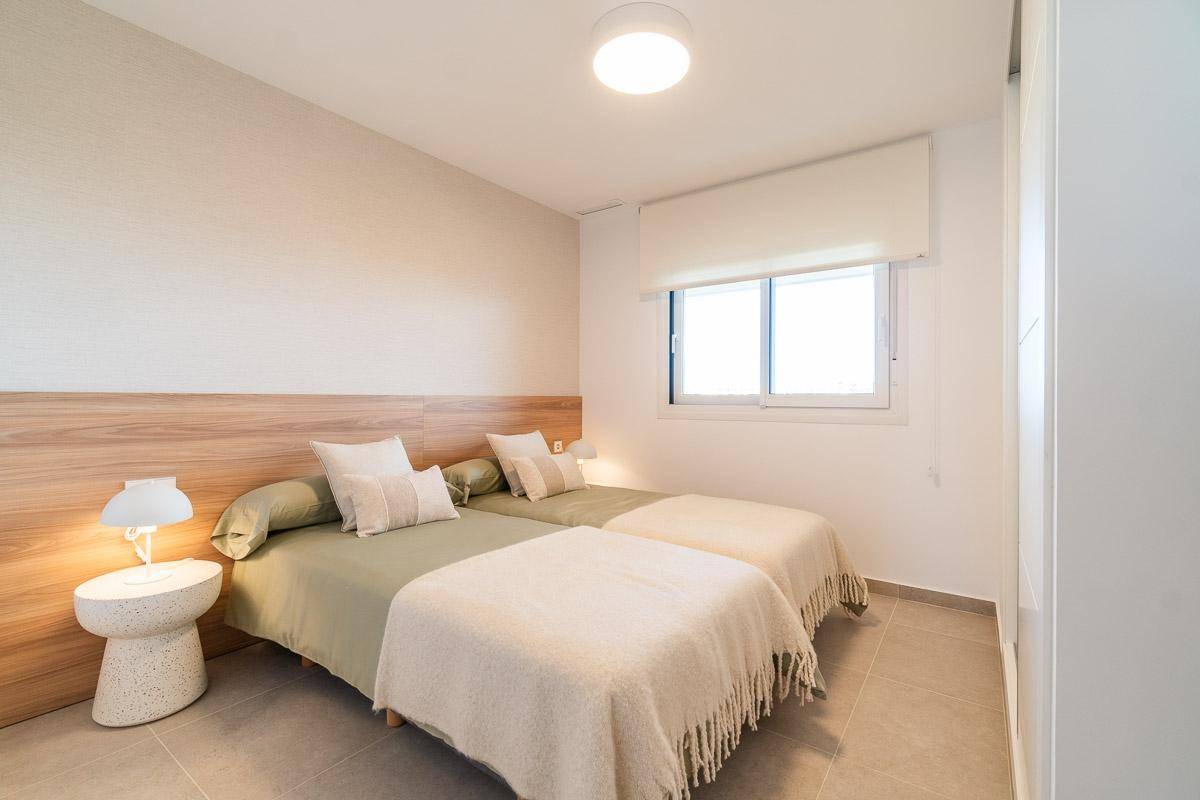 Schlafzimmer mit zwei Einzelbetten, einem Fenster und einem praktischen Einbauschrank.
