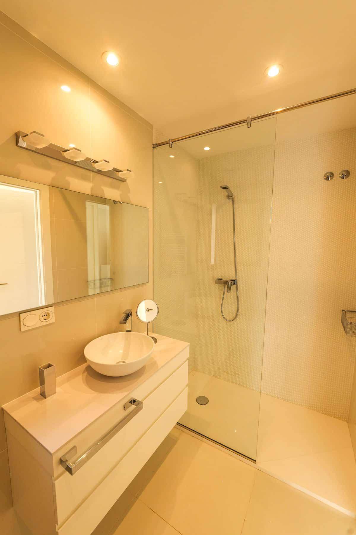 Helles Badezimmer mit begehbarer Dusche, modernem Waschtisch und großem Spiegel.