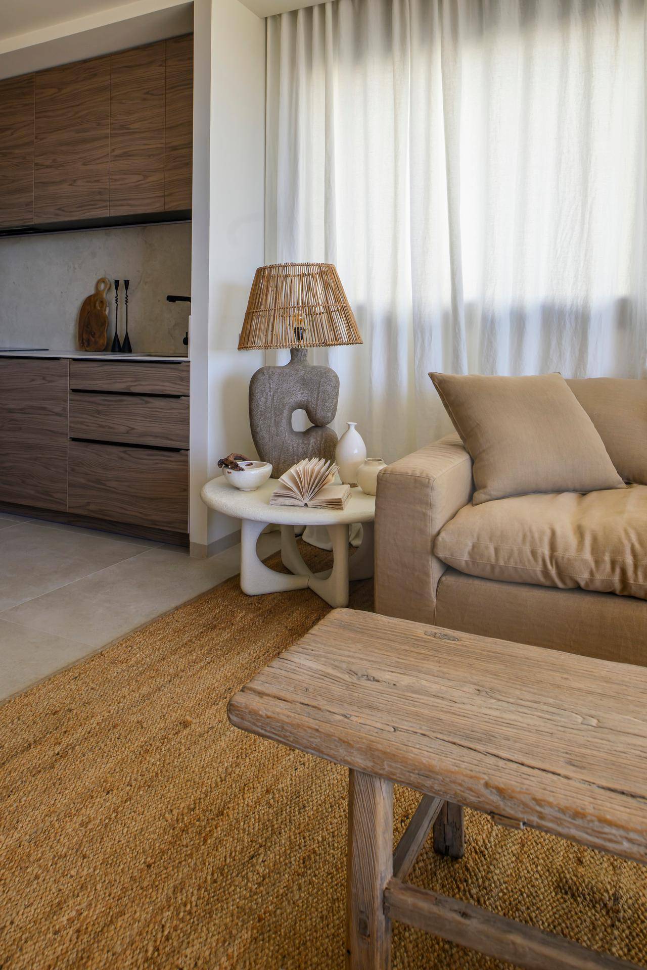 Gemütlicher Wohnbereich mit beigem Sofa, Holztisch und natürlicher Dekoration, durchflutet von Tageslicht.