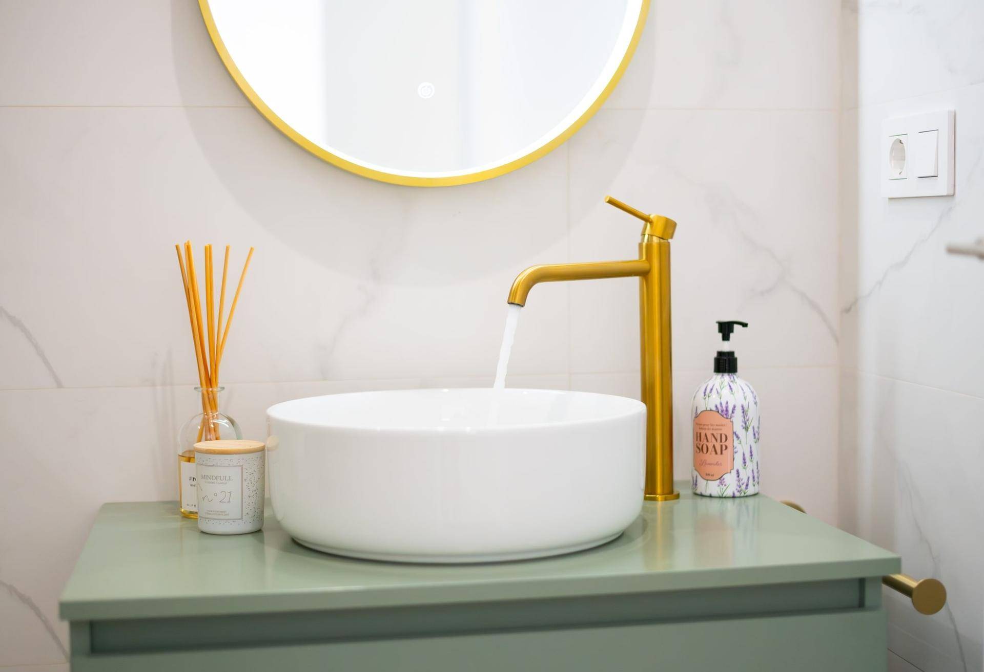 Detailaufnahme des modernen Waschtischs mit runder Schale und stilvollem goldenen Wasserhahn.