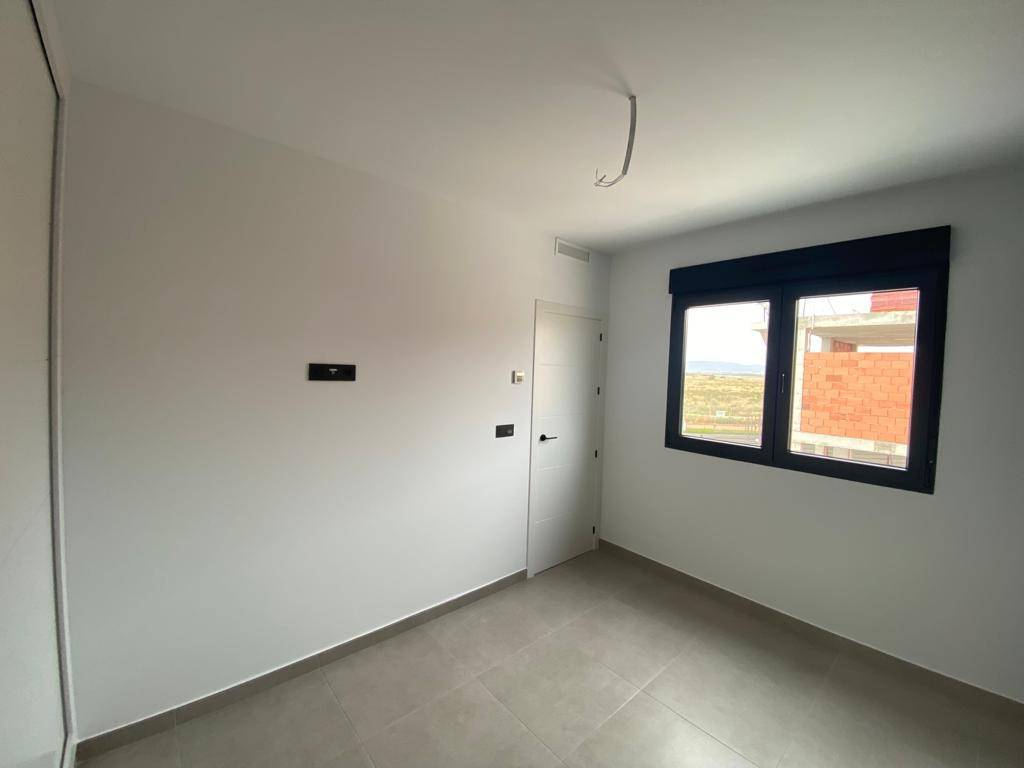 Leeres Schlafzimmer mit Fenster, Blick auf die Umgebung und modernen Fliesenboden.