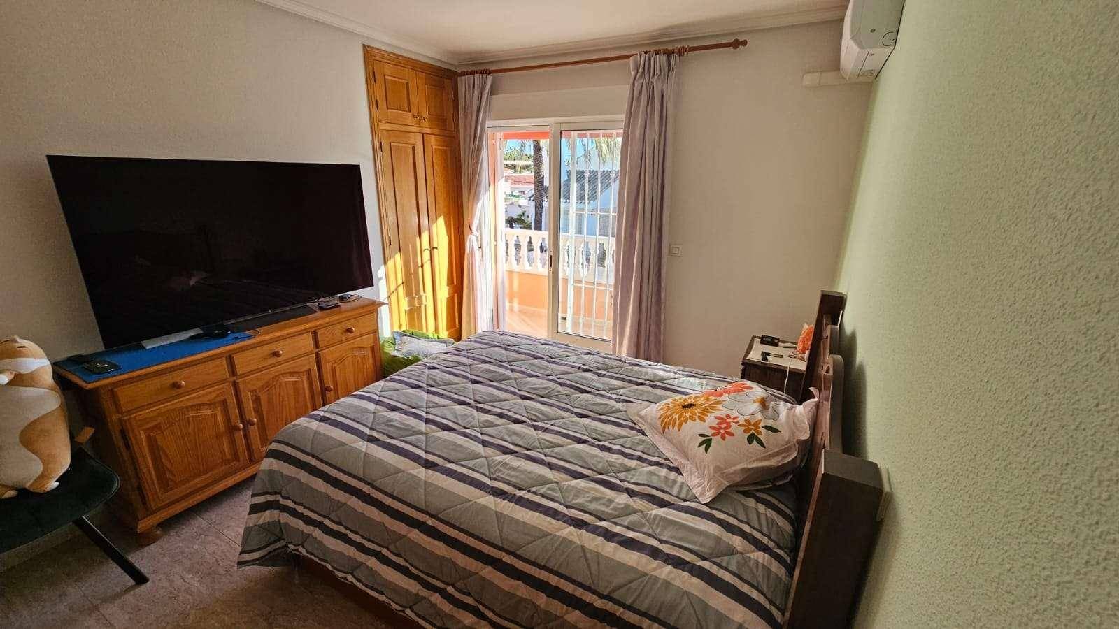 Schlafzimmer mit Doppelbett, großem Fernseher und Einbauschrank.