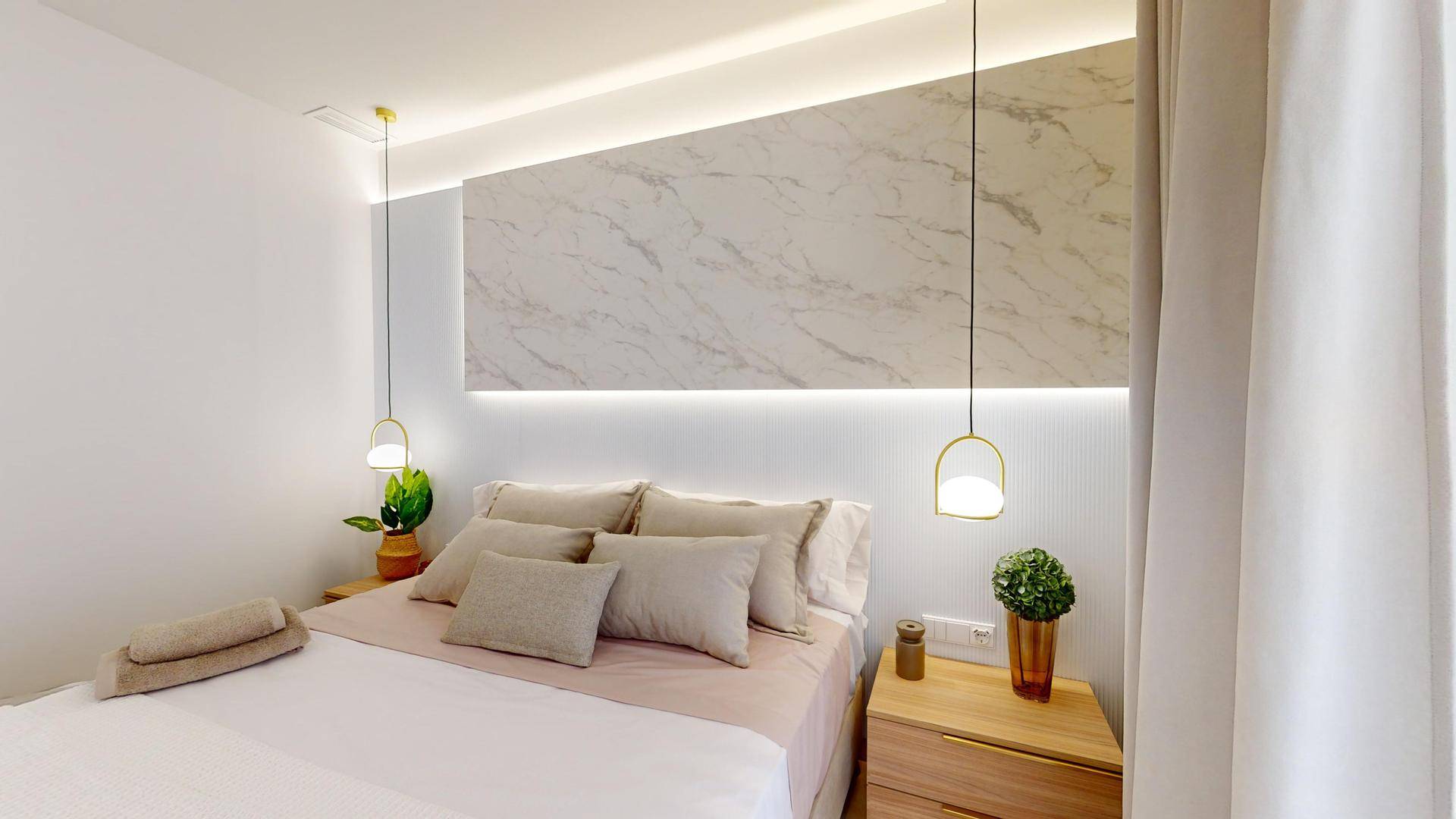 Gemütliches Schlafzimmer mit stilvollem Marmor-Kopfteil, indirekter Beleuchtung und modernen Hängelampen.