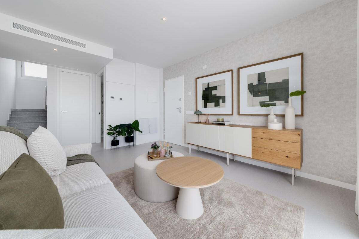 Helles Wohnzimmer mit moderner Einrichtung, Kunstwerken und Treppenzugang.