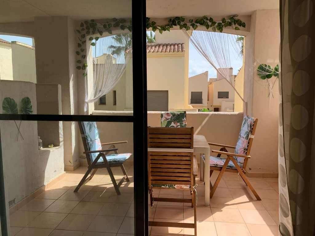 Blick vom Wohnzimmer auf den möblierten Balkon mit Sitzgelegenheiten und mediterraner Dekoration.