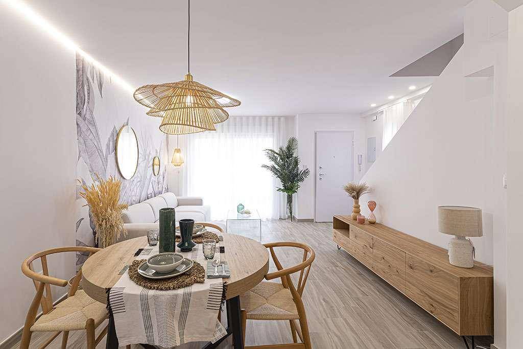 Heller Wohn-Essbereich mit modernem Holztisch, Rattanlampe und dekorativer Wandgestaltung.