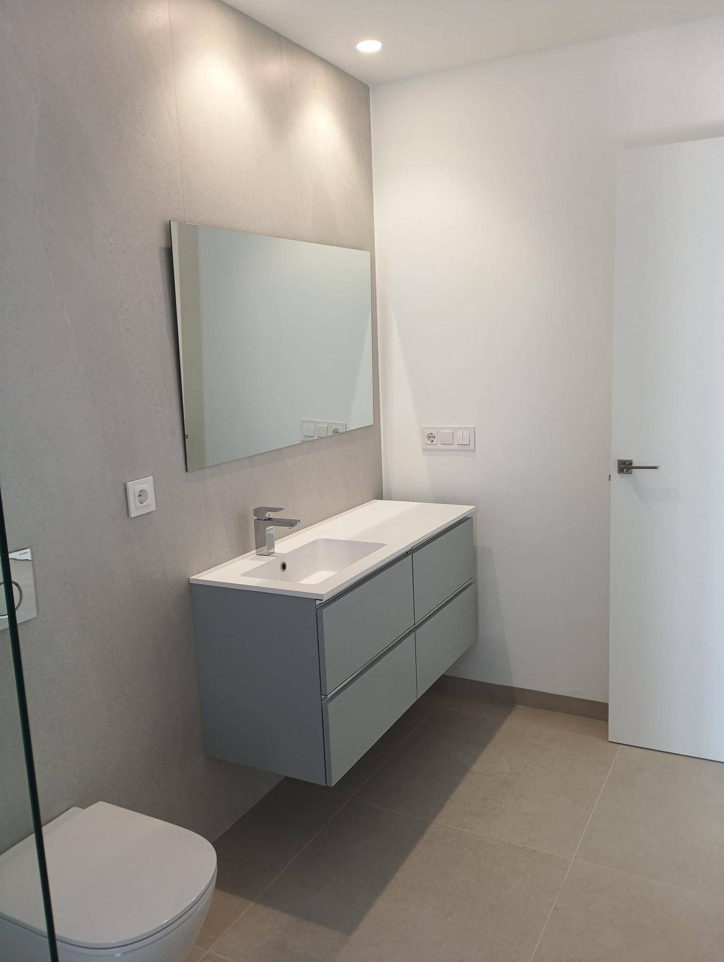 Modernes Badezimmer mit schwebendem Waschtisch, großem Spiegel und Wand-WC.