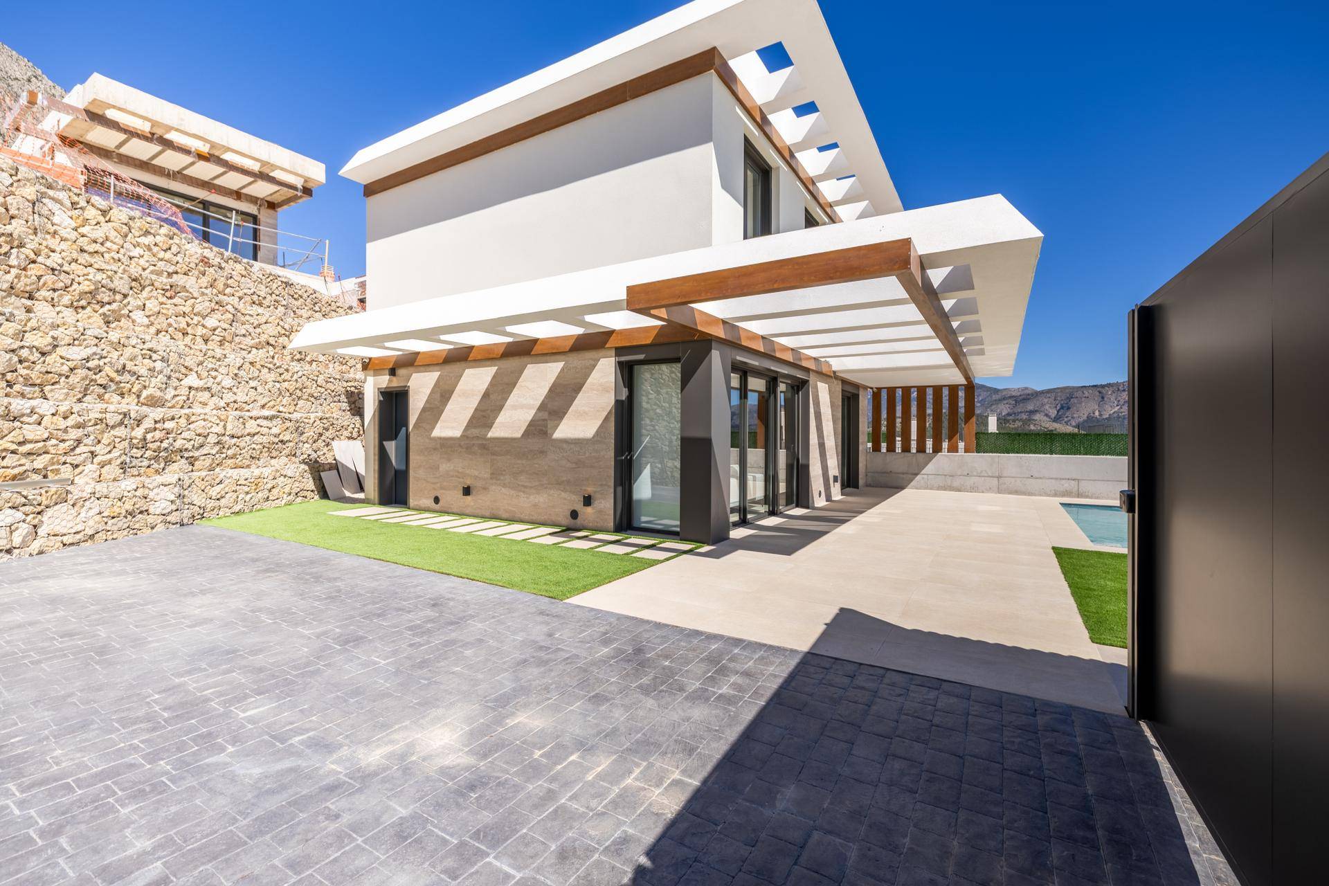 Seitliche Ansicht einer modernen Villa mit gepflasterter Auffahrt und Blick auf die umliegende Landschaft.