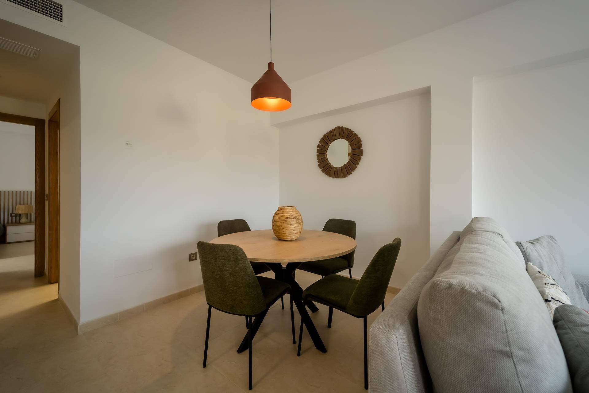 Essbereich mit rundem Holztisch und vier Stühlen, offen zum Wohnzimmer.