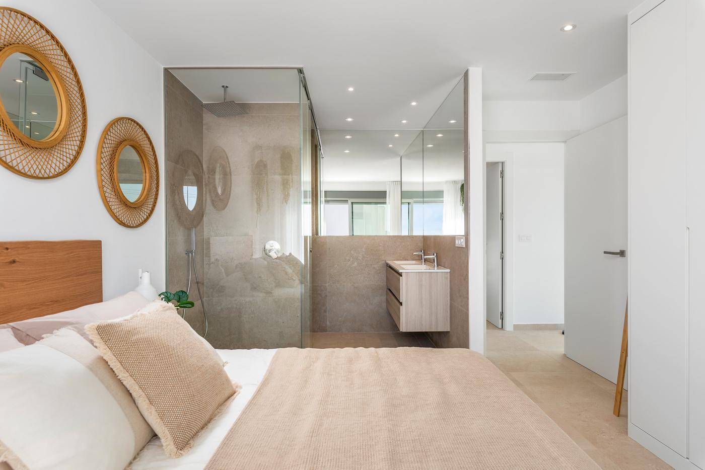 Schlafzimmer mit offenem Badezimmerbereich, begehbarer Dusche und Doppelwaschbecken.
