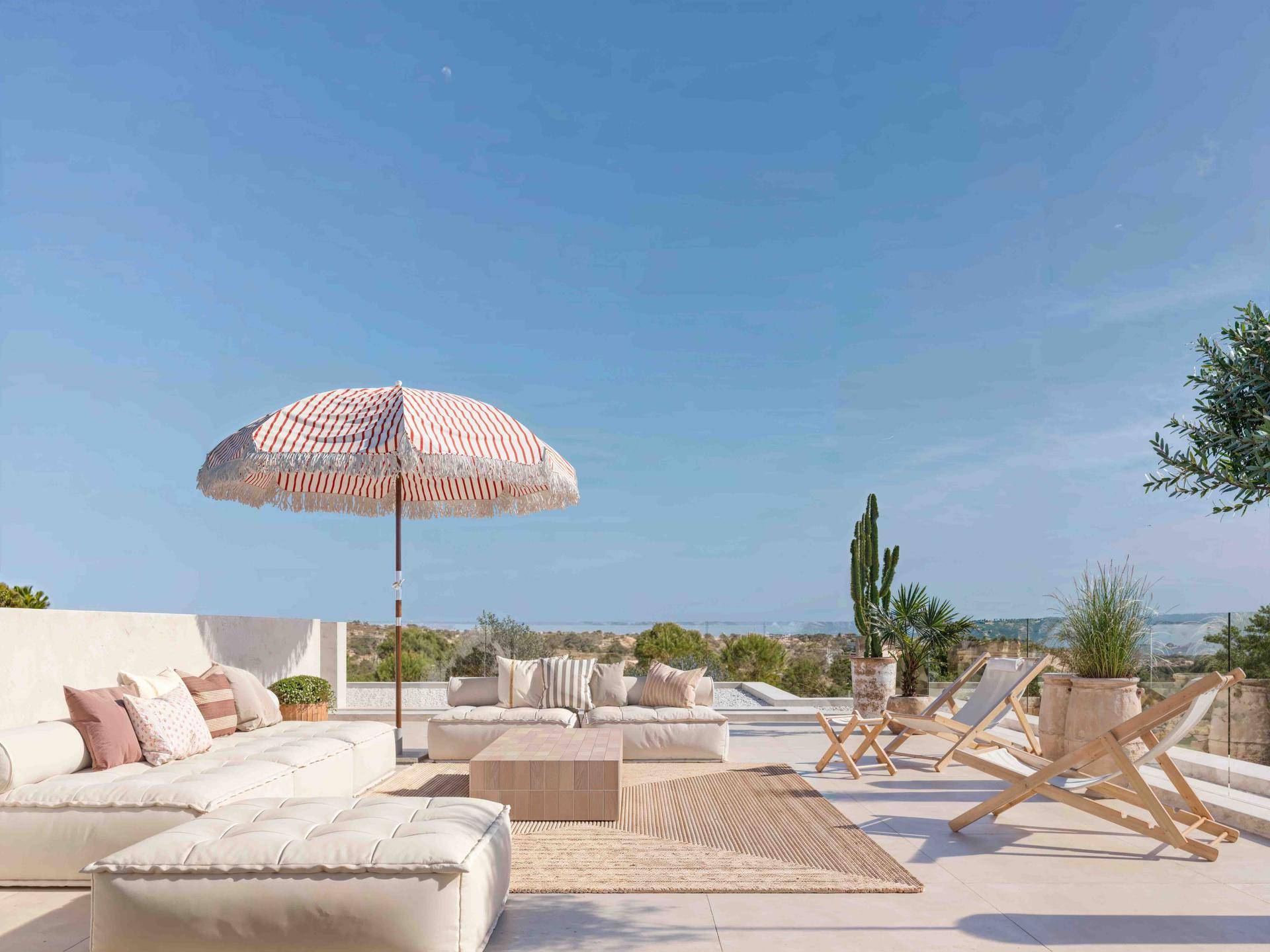 Großzügige Dachterrasse mit bequemen Lounge-Möbeln, Sonnenschirm und weitem Blick in die Landschaft.