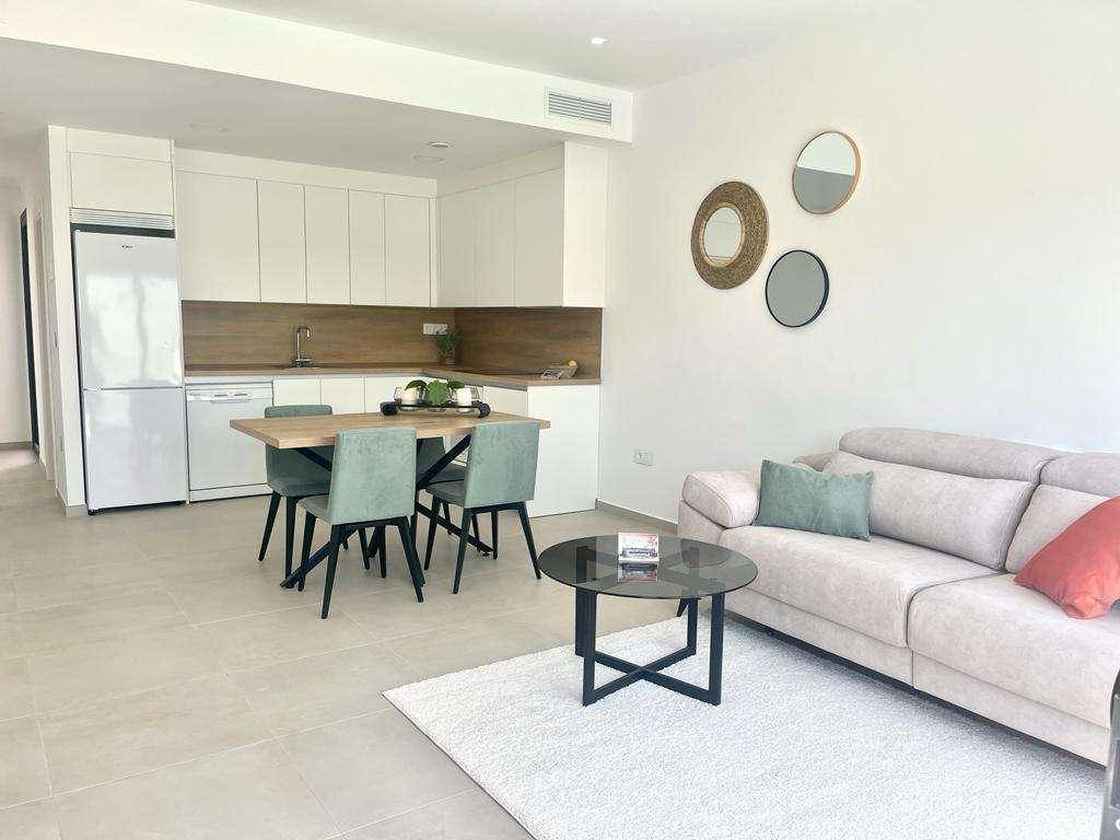 Heller offener Wohn- und Essbereich mit integrierter Küche und modernem Sofa.