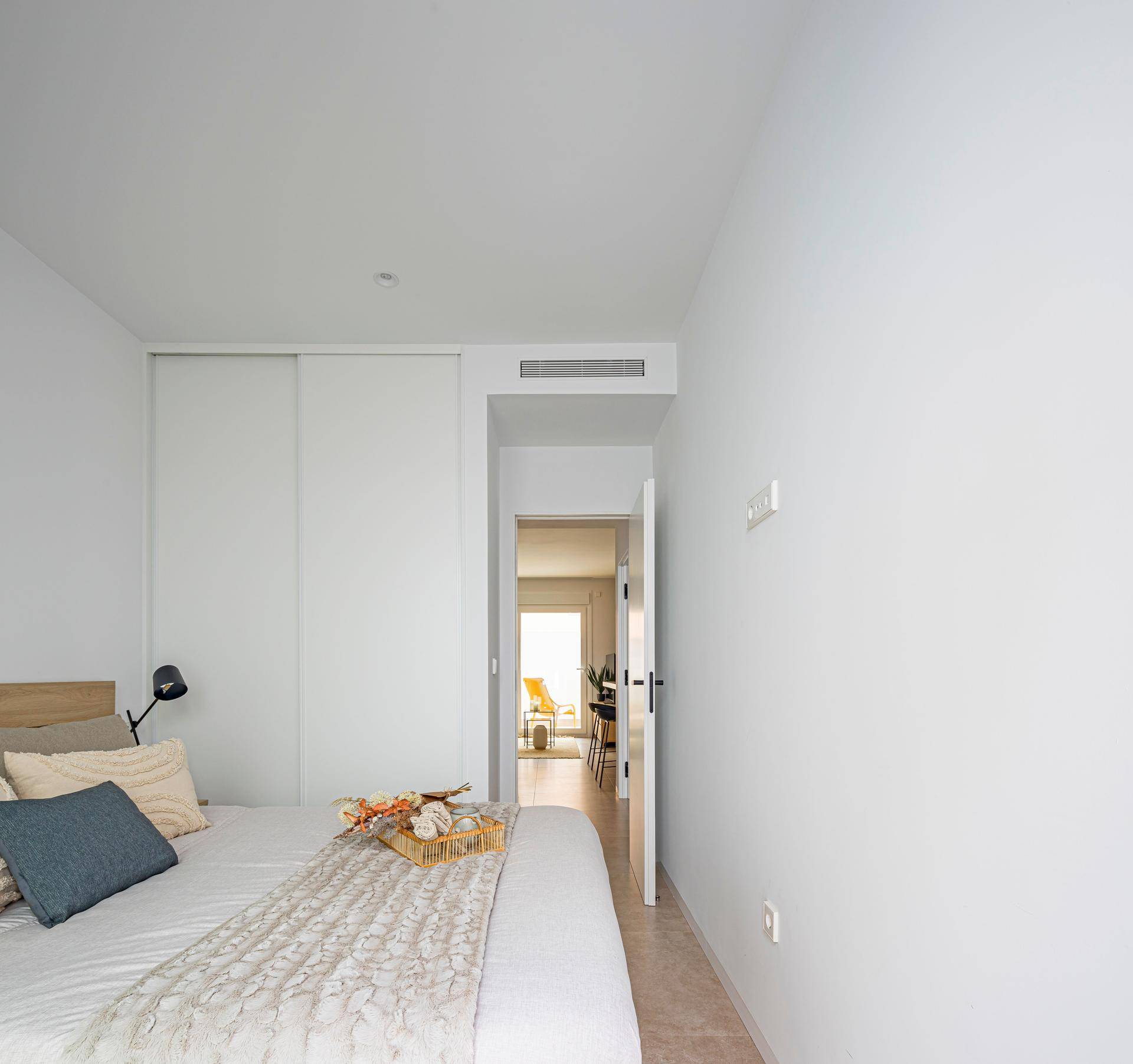 Schlafzimmer mit integriertem Kleiderschrank und Blick in den hellen Flur.