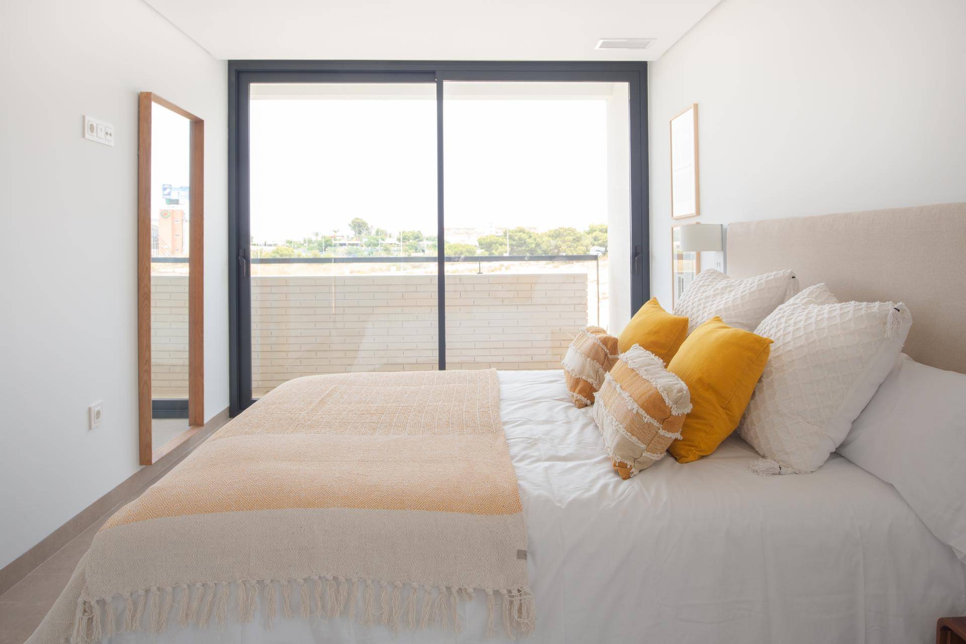 Schlafzimmer mit Doppelbett und großer Glasschiebetür, die Zugang zu einem Außenbereich bietet.