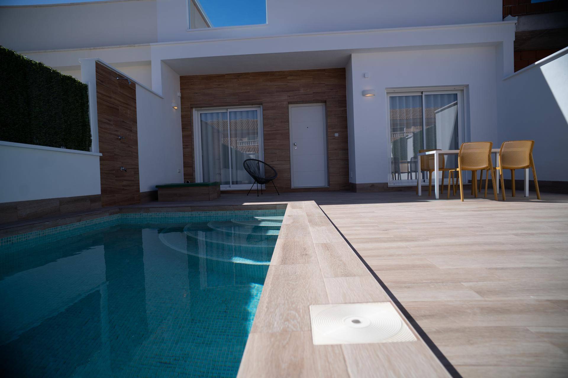 Detailansicht des privaten Pools mit Stufen und angrenzendem Holzdeck in sonniger Umgebung.
