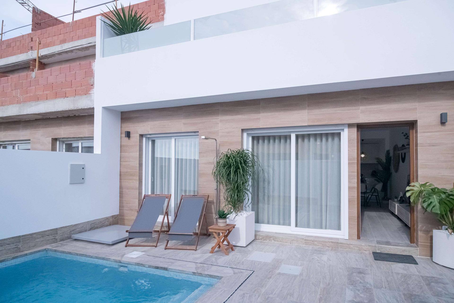 Sonniger Außenbereich mit kleinem Pool, Liegestühlen und direktem Zugang zum Haus.