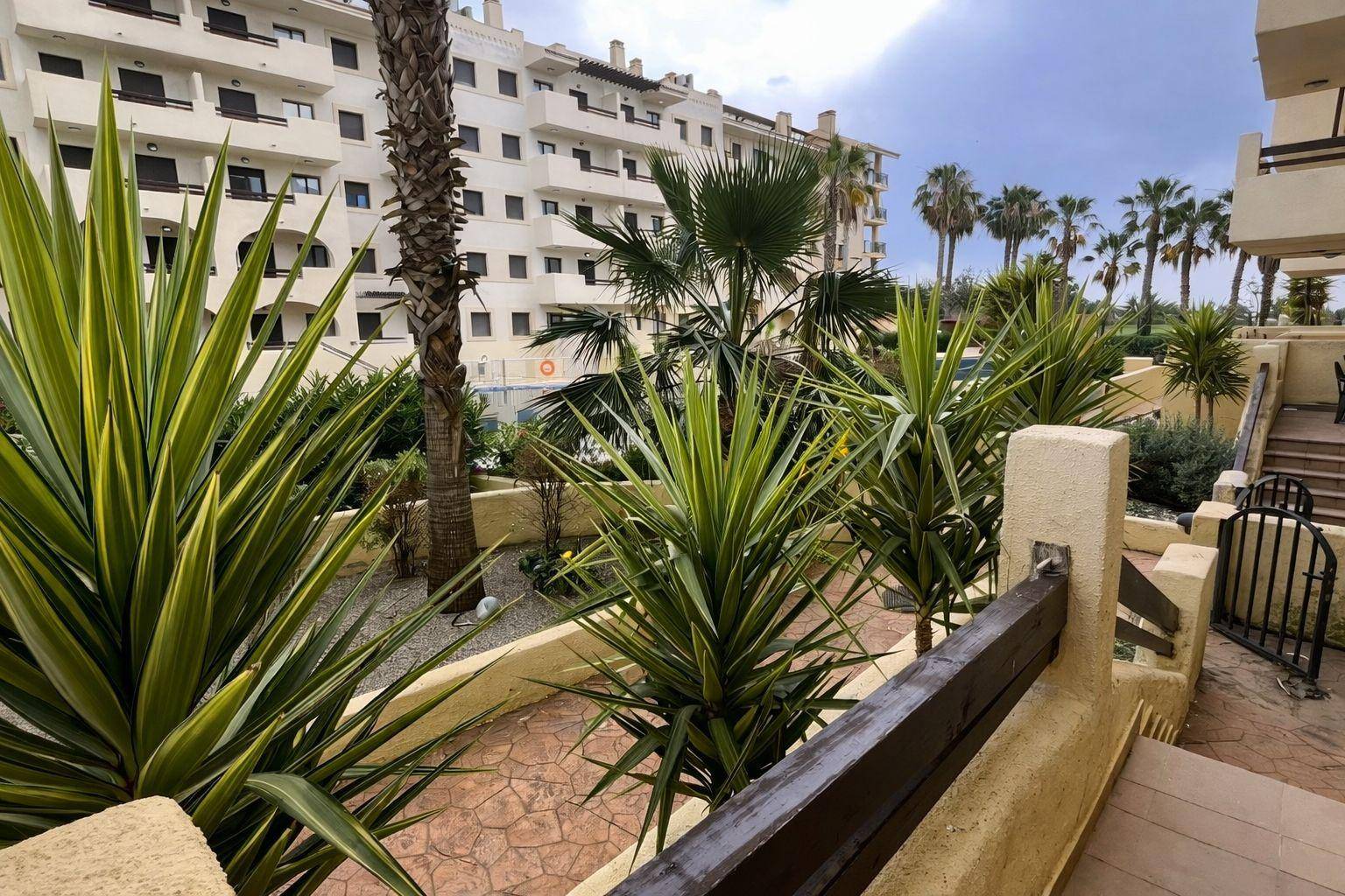 Mediterraner Gartenbereich mit exotischen Pflanzen und Blick auf die Apartmentgebäude.