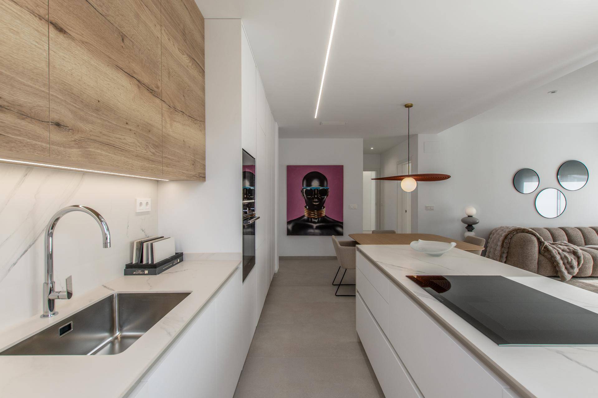 Moderne offene Küche mit Holz- und weißen Fronten, integriert in den Wohnbereich.