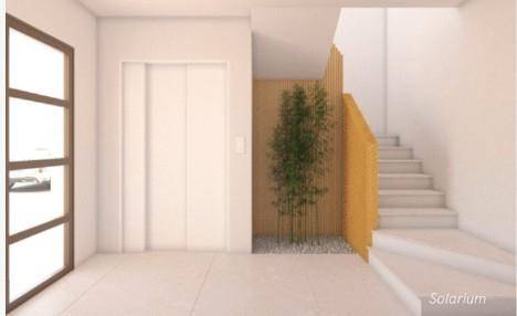 Heller Eingangsbereich mit Aufzug, Treppe und dekorativer Bepflanzung.
