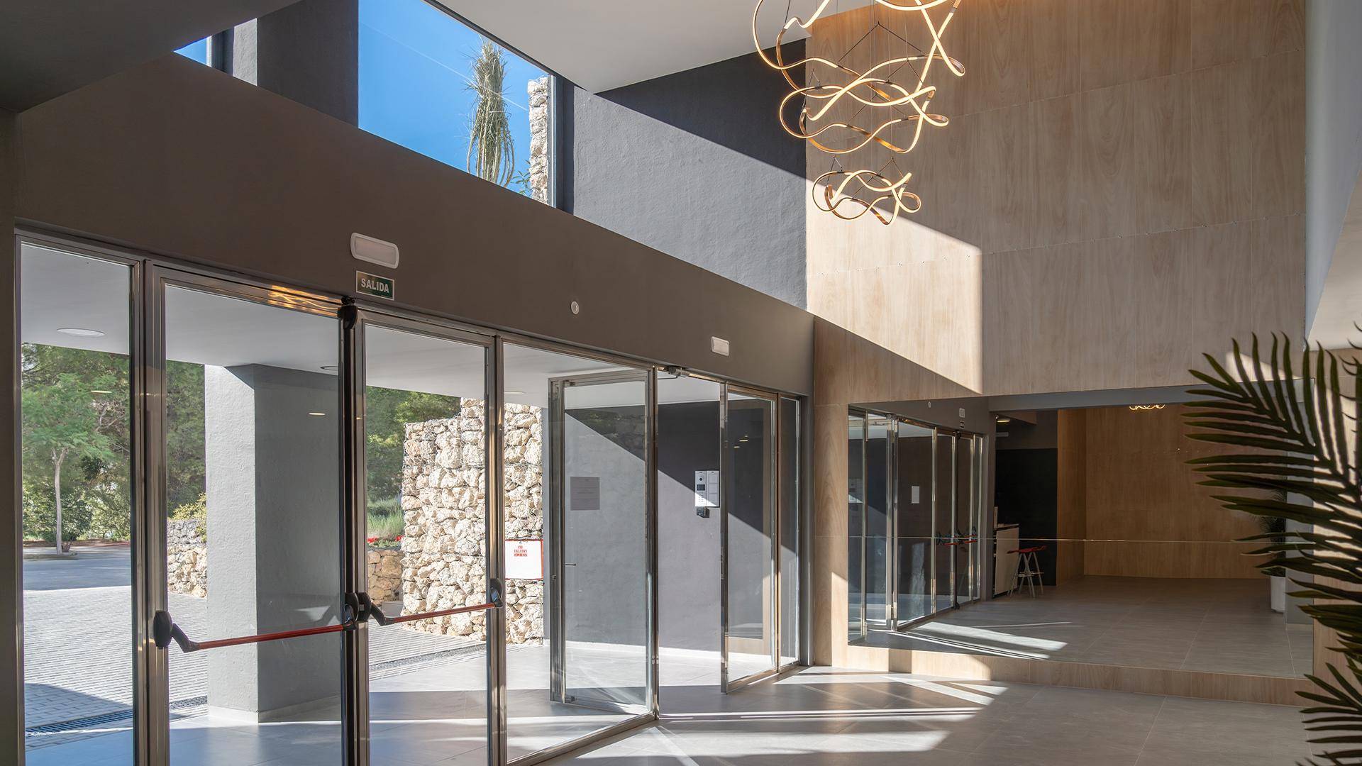 Heller und geräumiger Eingangsbereich mit großen Glasfronten und moderner Deckenbeleuchtung.