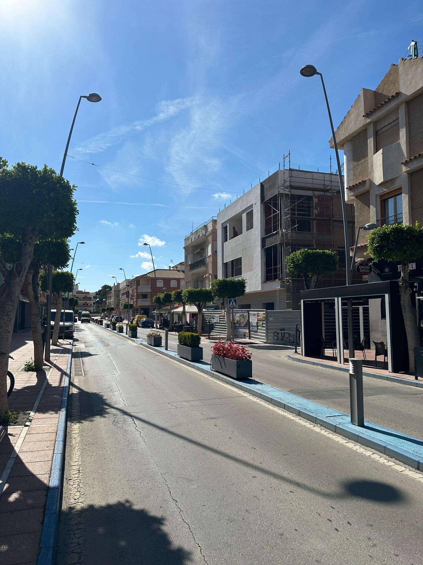 Panoramablick auf die Straße mit Gebäuden, Bäumen und einem im Bau befindlichen Objekt.