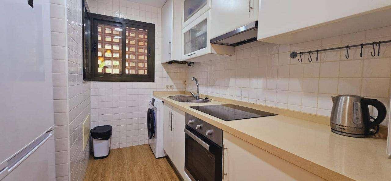 Funktionale Küche mit weißen Schränken, Induktionskochfeld und Fenster.
