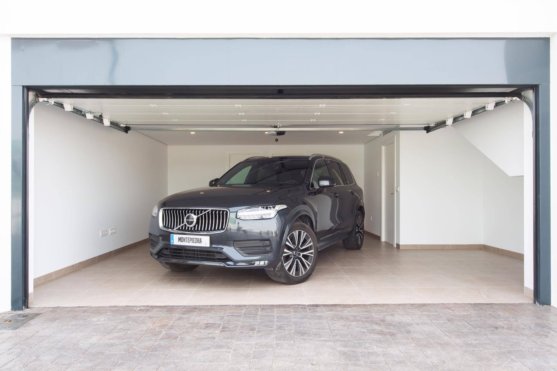 Geräumige und helle Garage mit geöffnetem Tor und einem geparkten Fahrzeug.