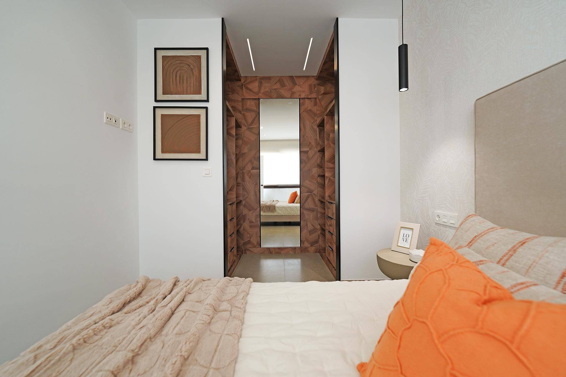Schlafzimmer mit bequemem Bett und direktem Zugang zu einem begehbaren Kleiderschrank mit Spiegel.