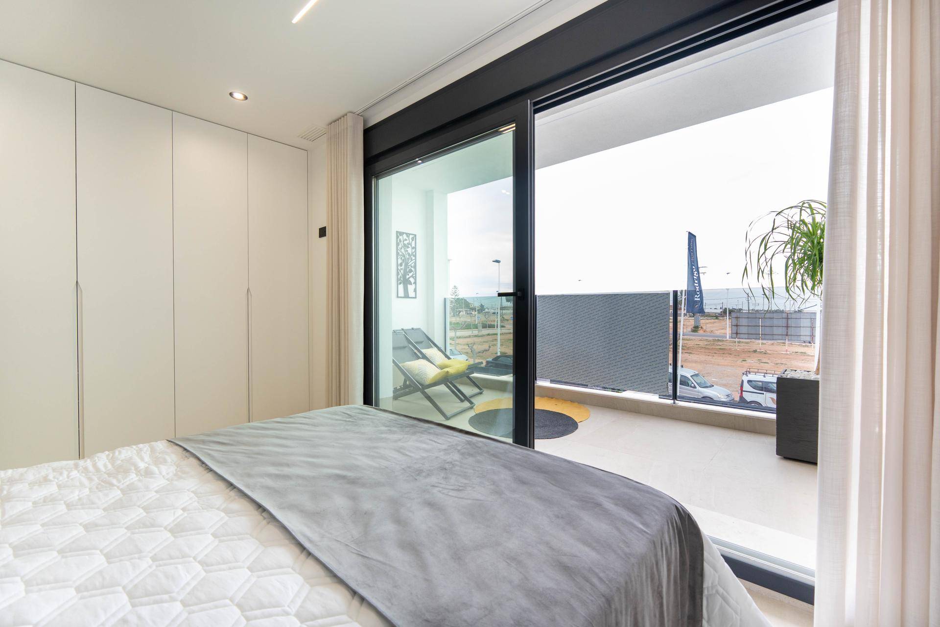 Helles Schlafzimmer mit großen Fenstern, Einbauschränken und direktem Zugang zum Balkon.