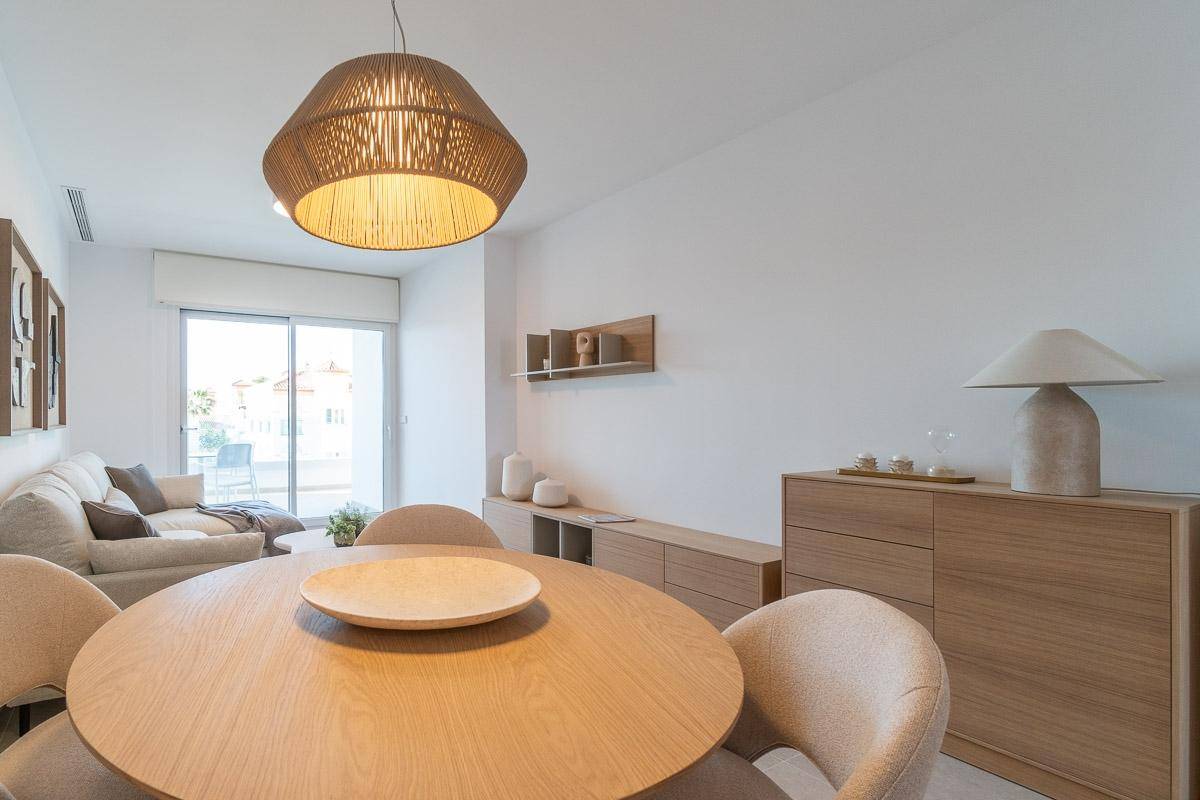 Gemütlicher Wohn-Essbereich mit rundem Esstisch und Sofa, mit Zugang zu einem sonnigen Balkon.