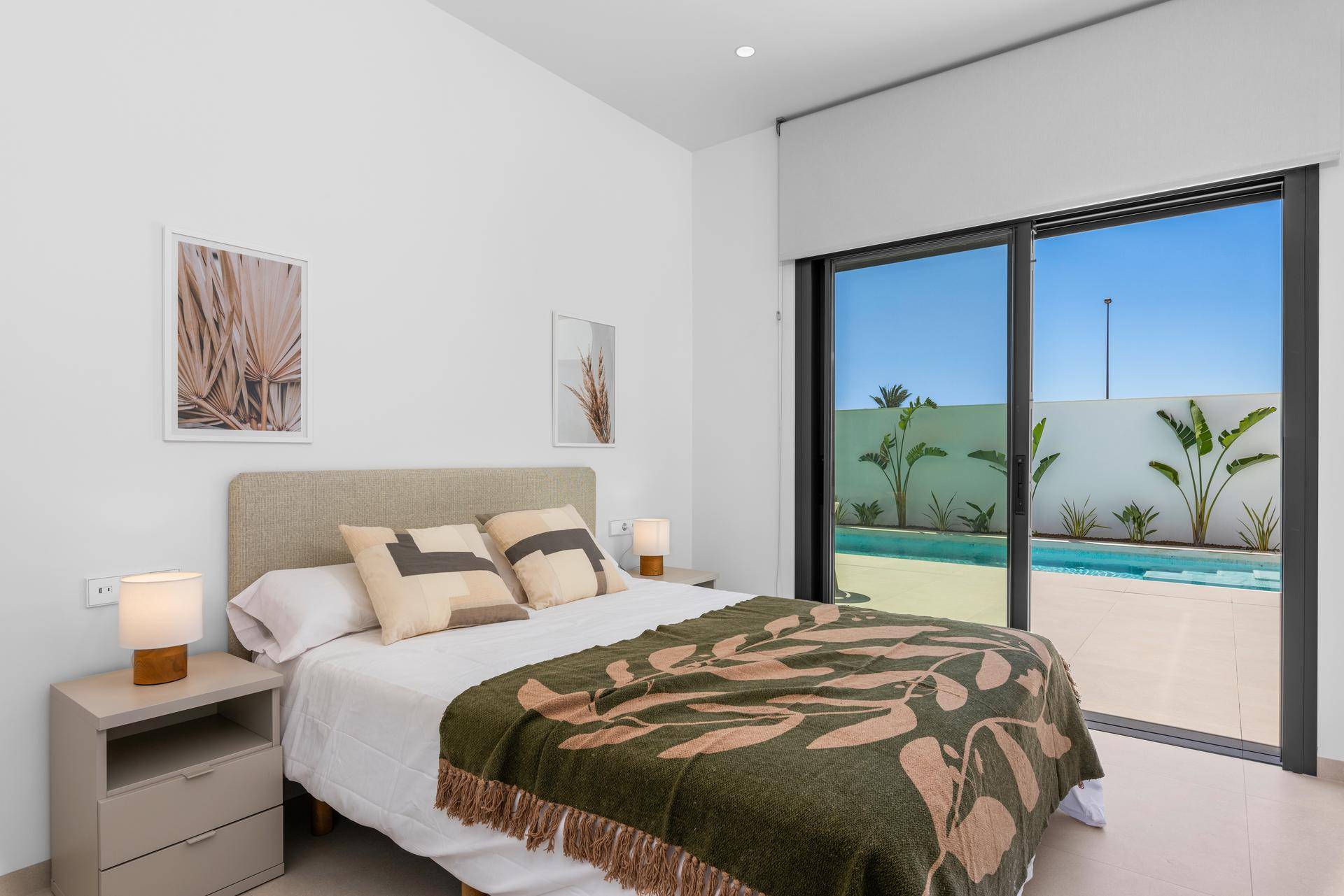 Schlafzimmer mit großem Fenster, Blick auf den Pool und direkten Zugang zum Außenbereich.