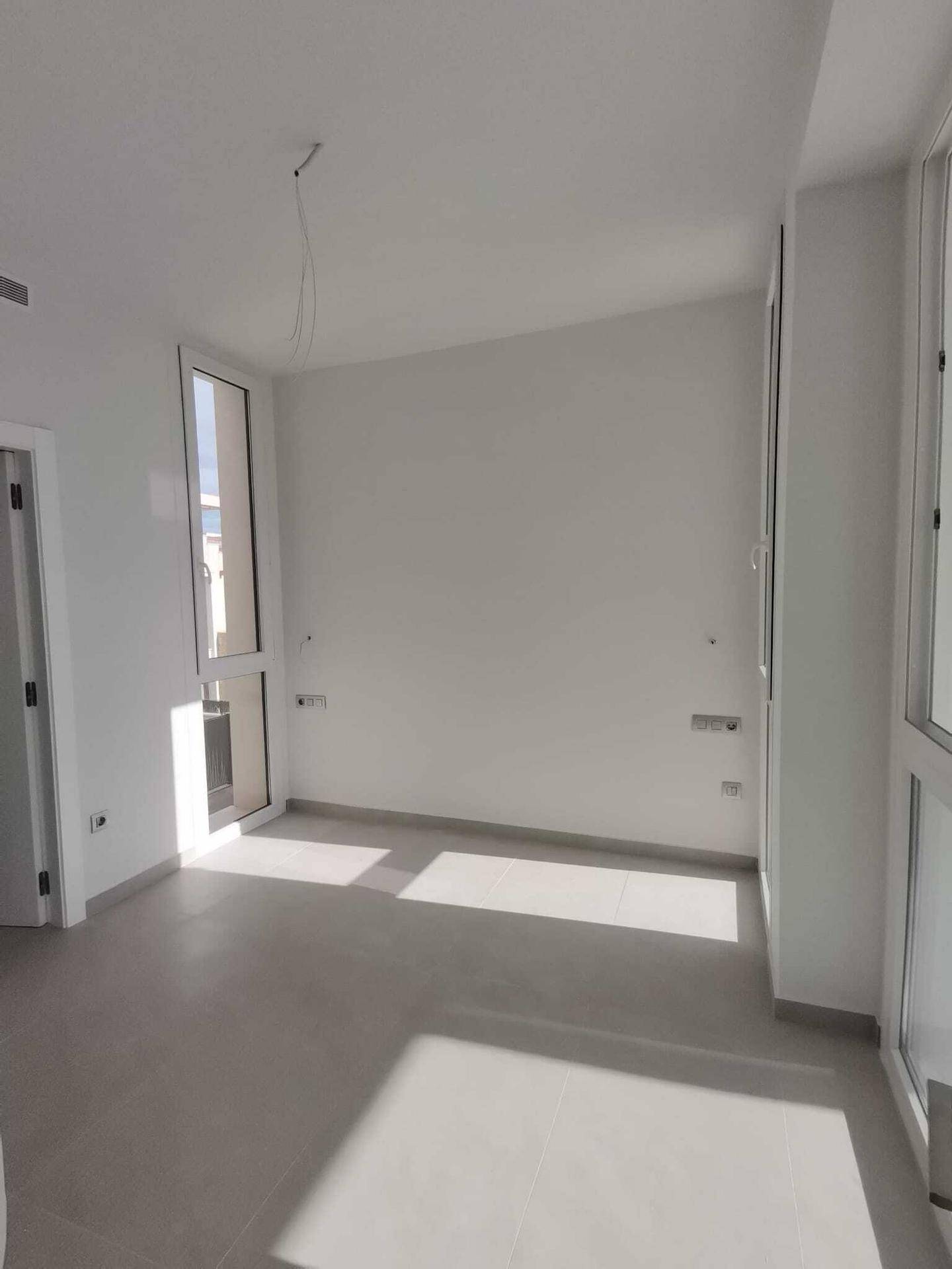 Leeres Schlafzimmer mit großen Fenstern und hellem Fliesenboden, ideal für individuelle Gestaltung.
