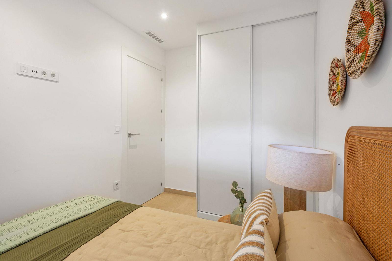 Schlafzimmer mit integrierten Schiebetürenschränken und schlichter, funktionaler Einrichtung.