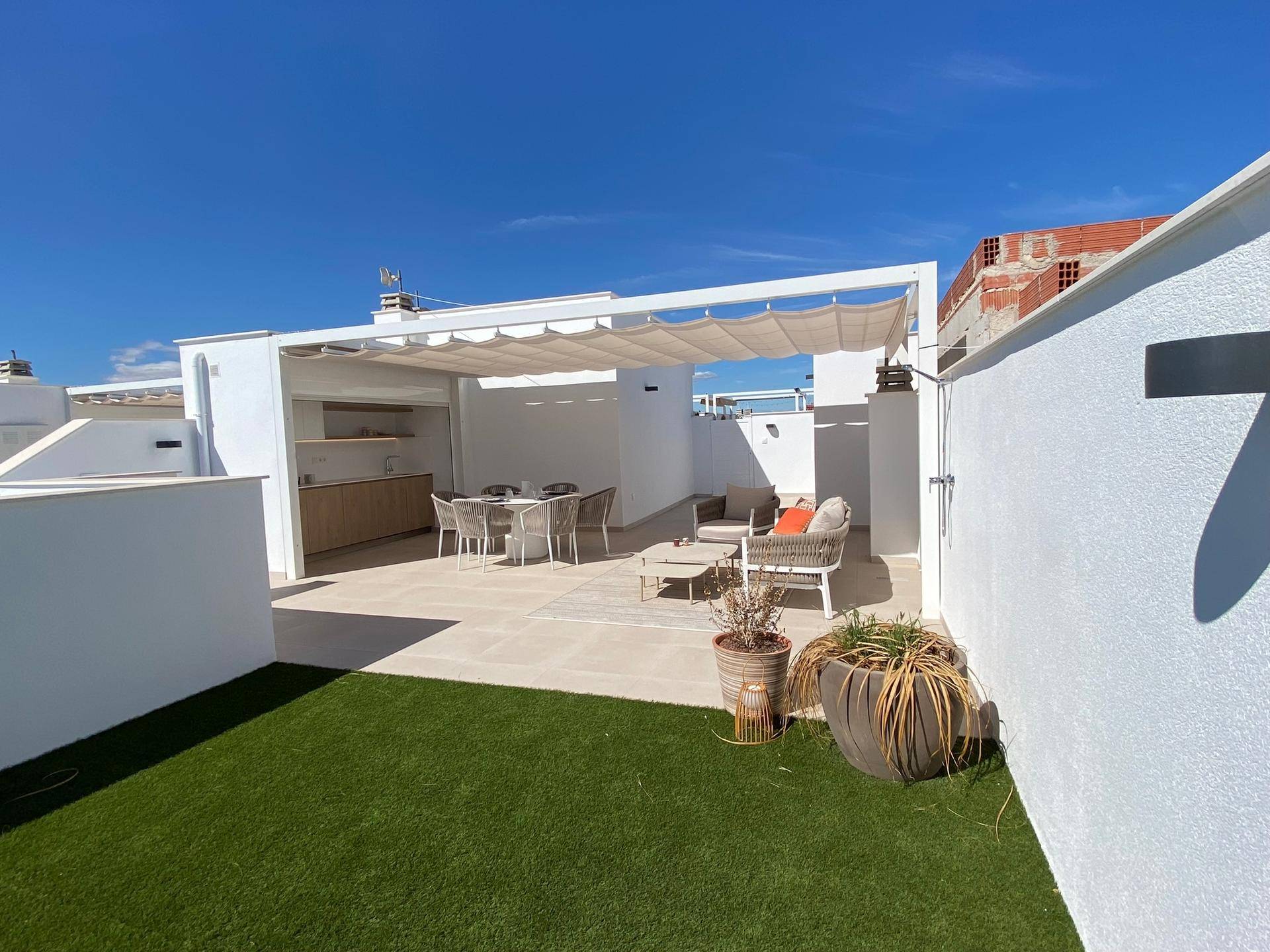 Weitläufige Dachterrasse mit Außenküche, Essbereich und einem grünen Rasenstück.