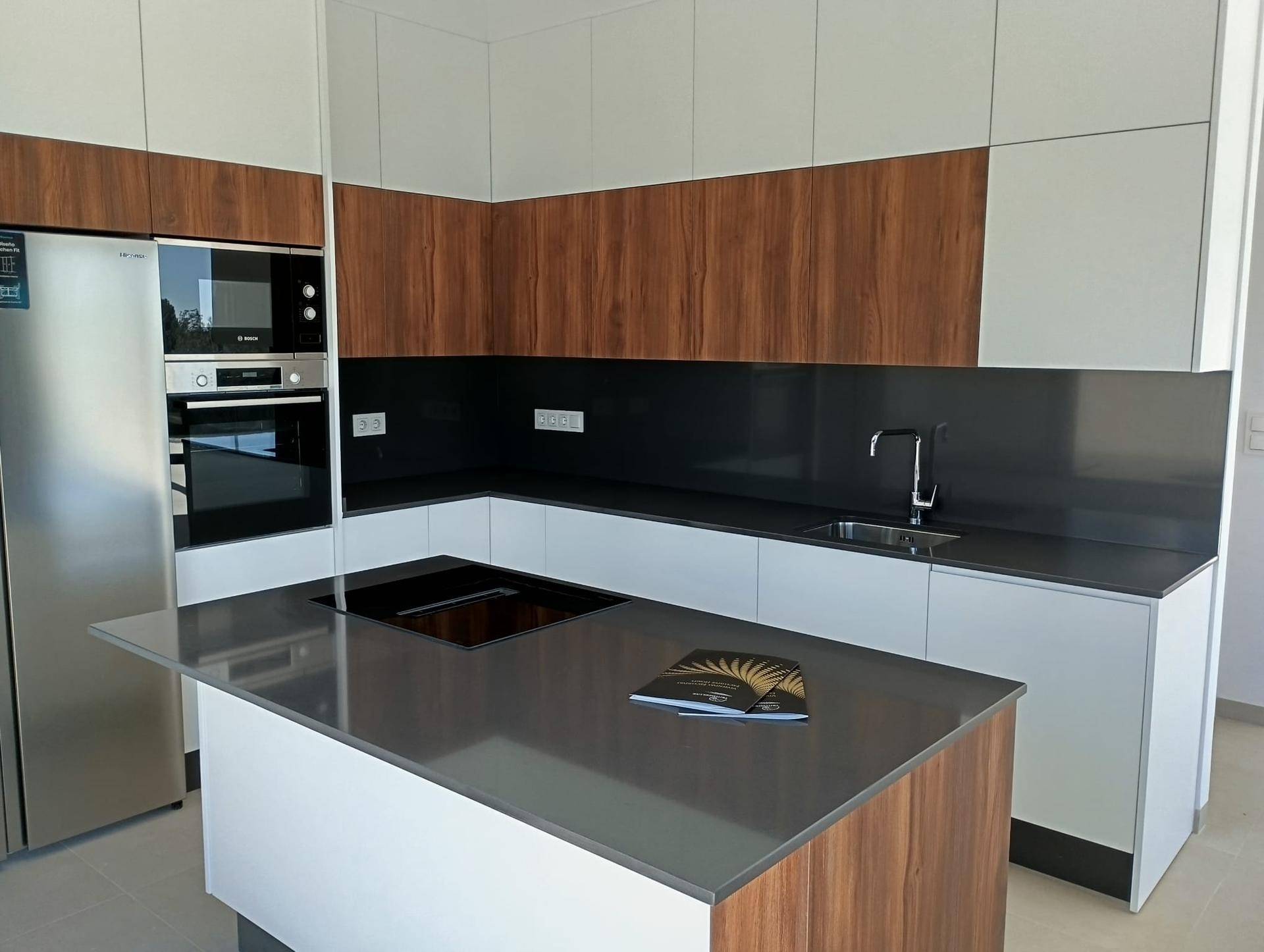 Hochwertige Einbauküche mit Holz- und Weißfronten, integrierten Geräten und Kochinsel.