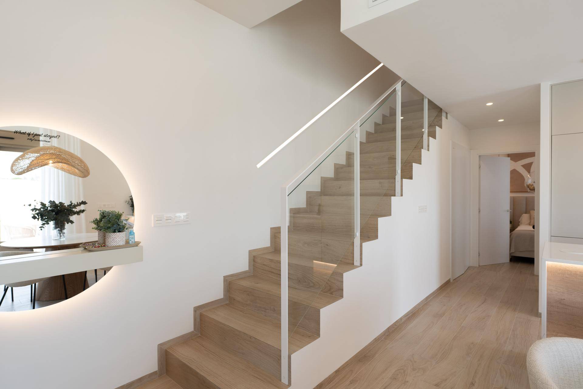 Moderne Treppe mit Holzstufen und Glasgeländer, die die Etagen verbindet.