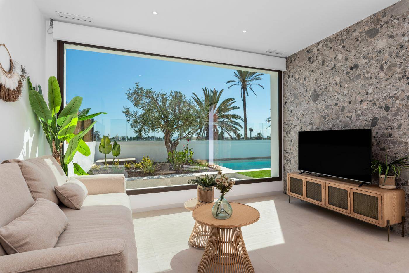 Modernes Wohnzimmer mit großem Fenster, Blick auf den Garten und den Poolbereich.