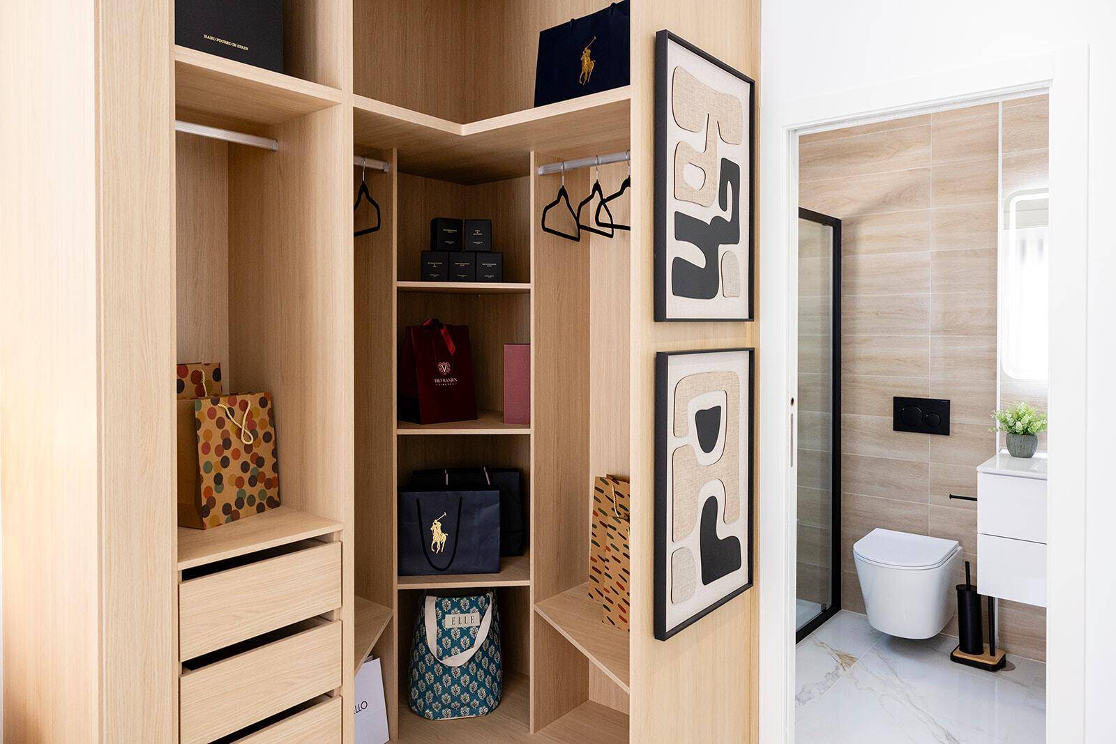 Offener Kleiderschrank mit Blick auf das moderne Badezimmer mit Wand-WC.