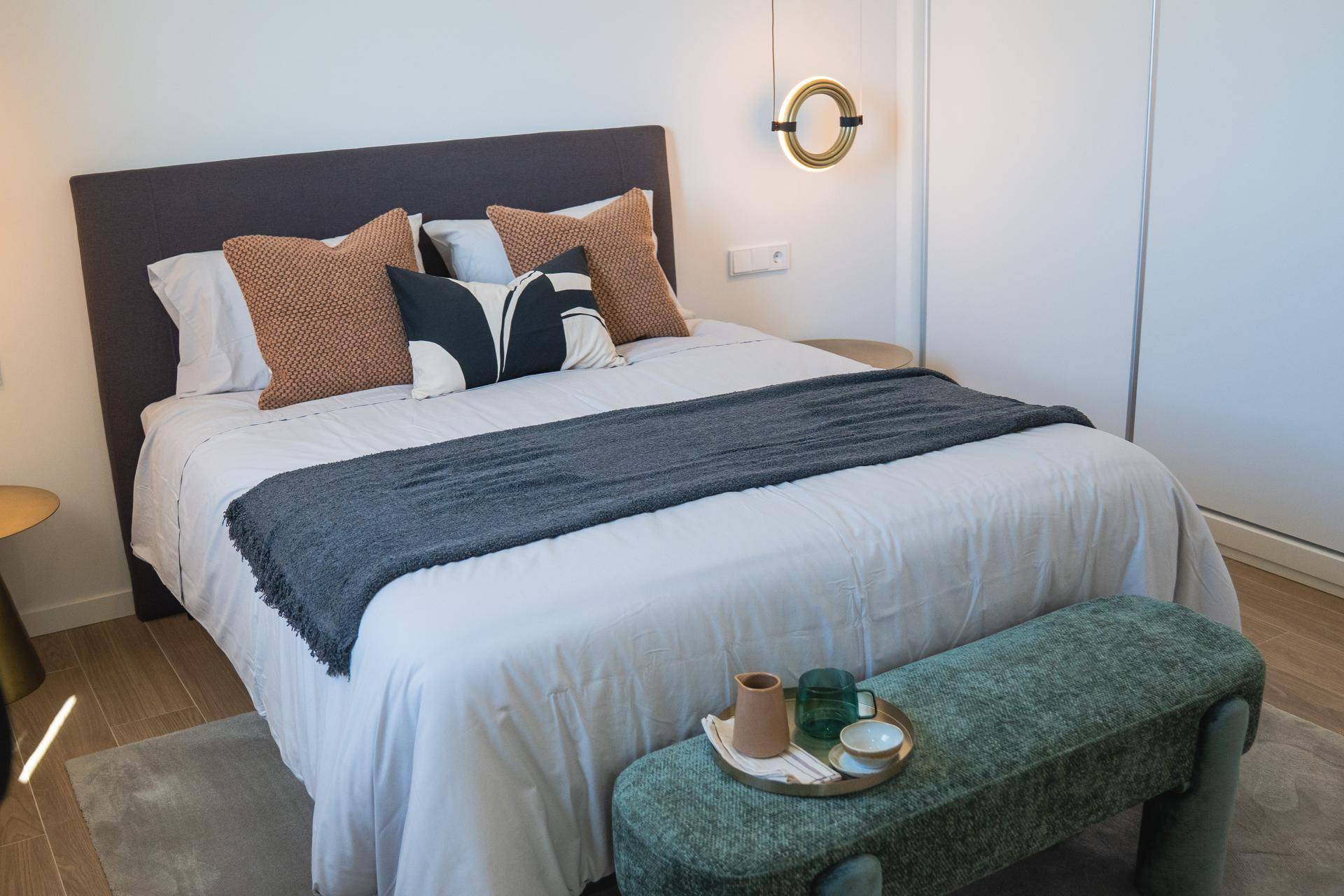 Modernes Schlafzimmer mit Doppelbett, Sitzbank und Einbauschrank in hellem Design.