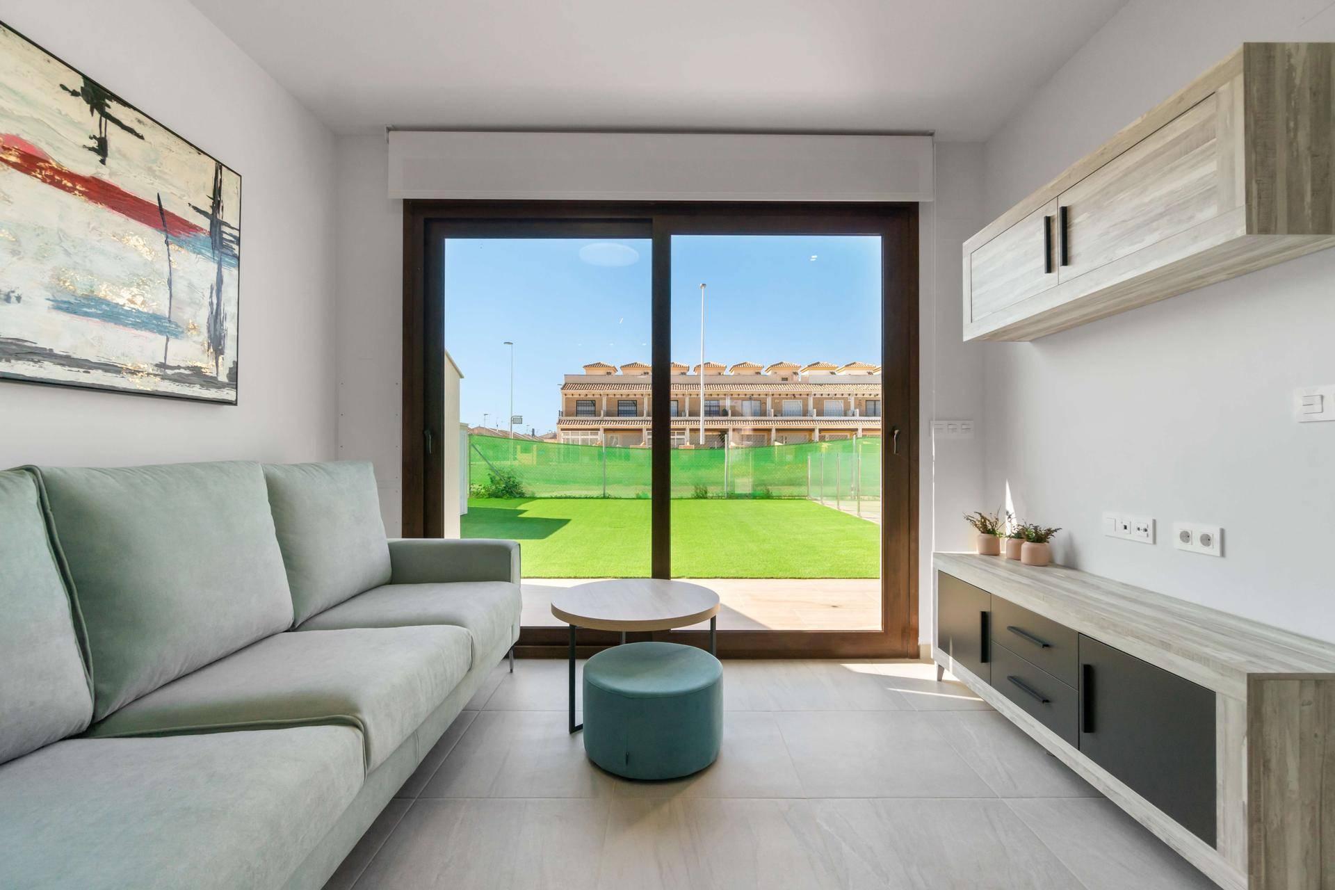 Gemütlicher Wohnbereich mit hellem Sofa und großer Glasschiebetür mit Blick ins Grüne.