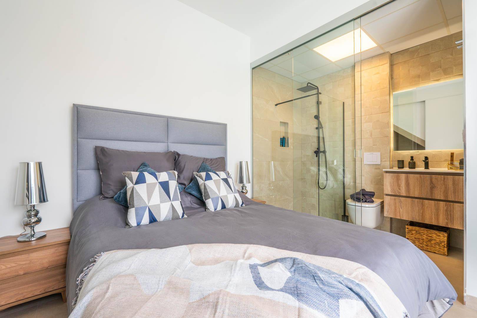 Schlafzimmer mit integriertem, modernem Badbereich und großem Bett.