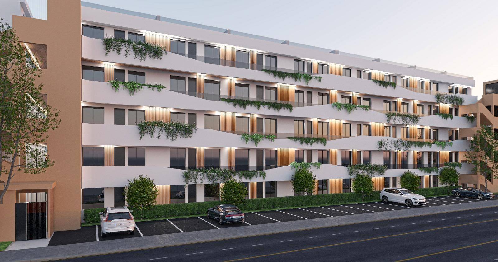 Moderne Wohnanlage mit mehreren Etagen, begrünten Balkonen und Parkplätzen entlang der Straße.