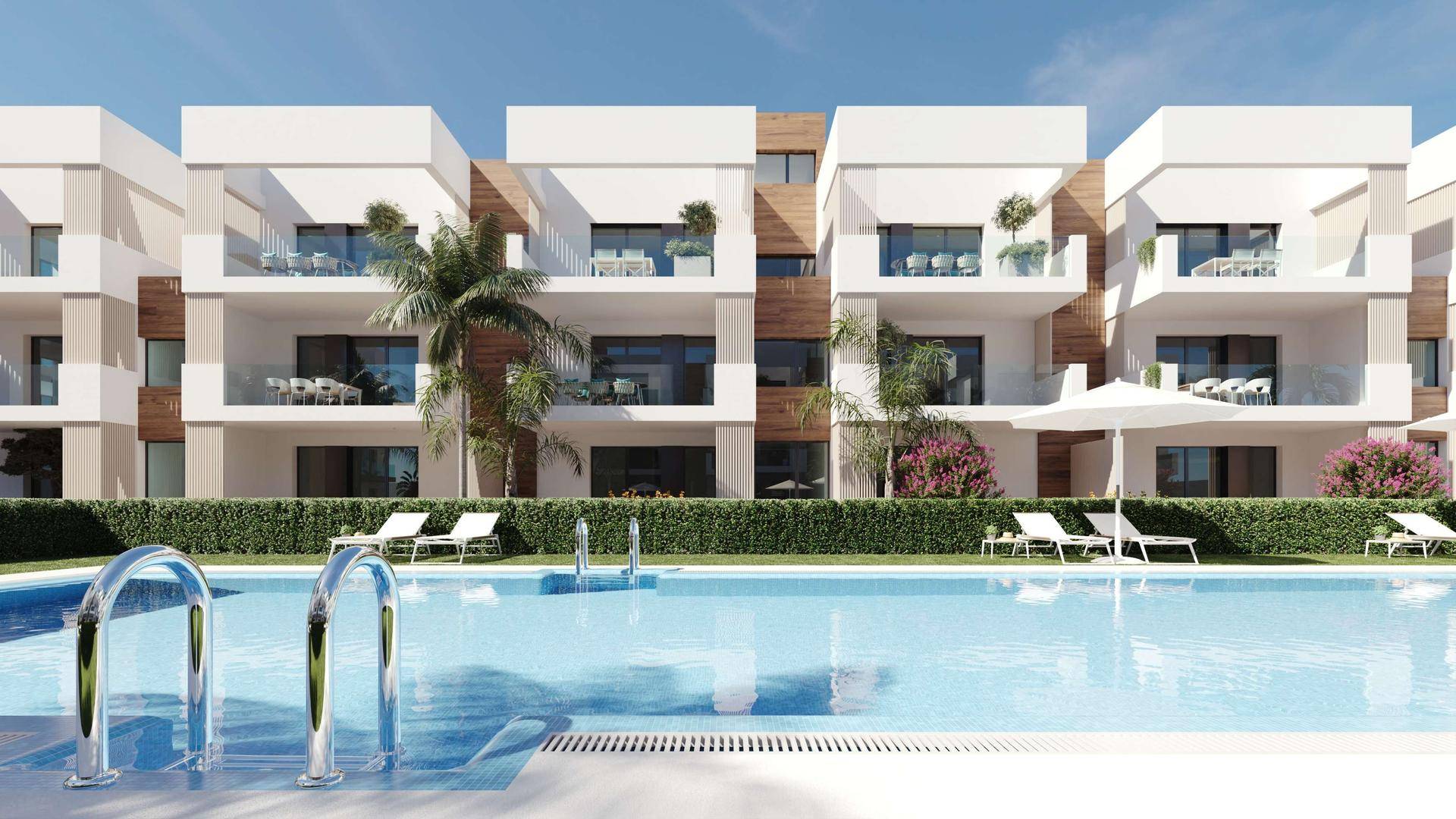 Ansicht der modernen Wohngebäude mit Balkonen und einem großen Gemeinschaftspool mit Liegestühlen.