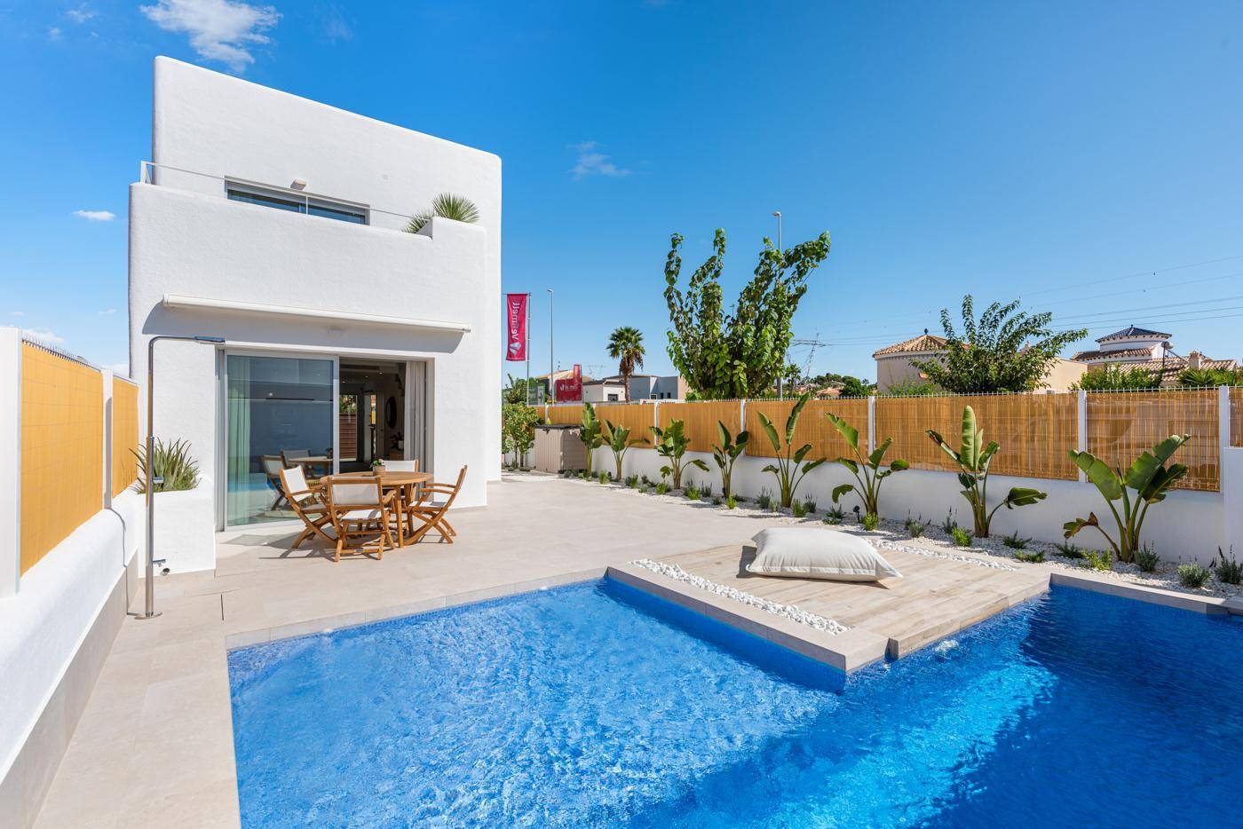 Helle moderne Villa mit privatem Pool und möblierter Terrasse unter strahlend blauem Himmel.