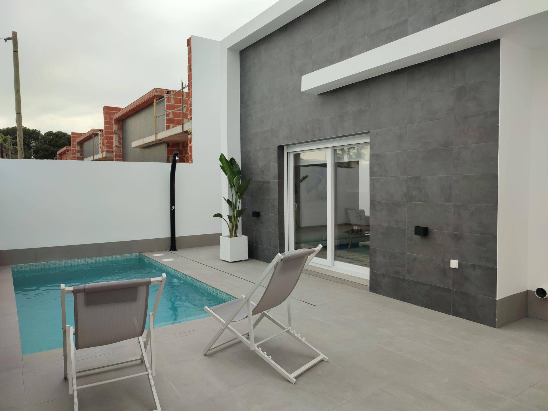 Moderner Außenbereich mit kleinem Pool, Liegestühlen und Blick auf die umliegende Bebauung.