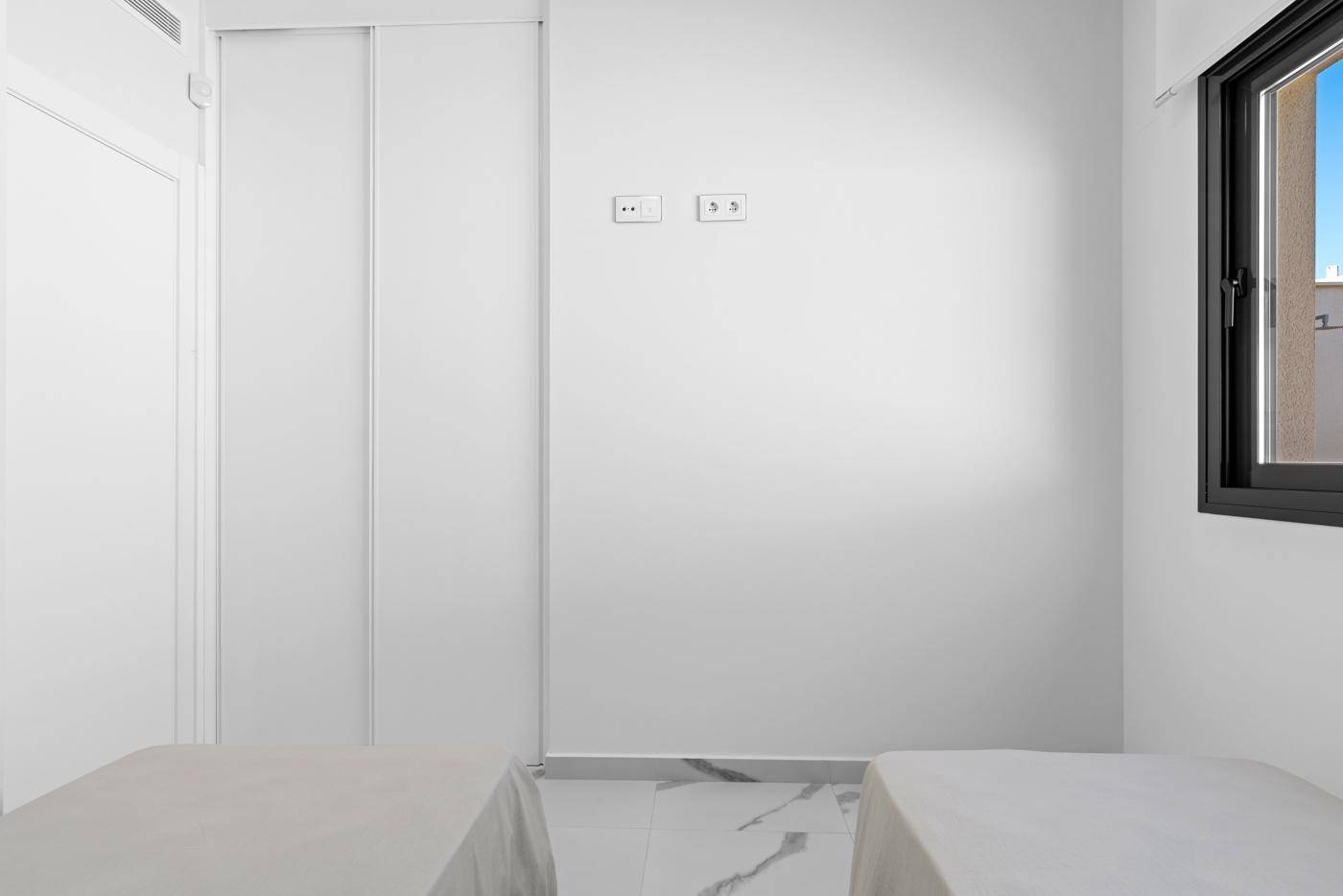 Helles Schlafzimmer mit zwei Einzelbetten und weißem Einbauschrank.