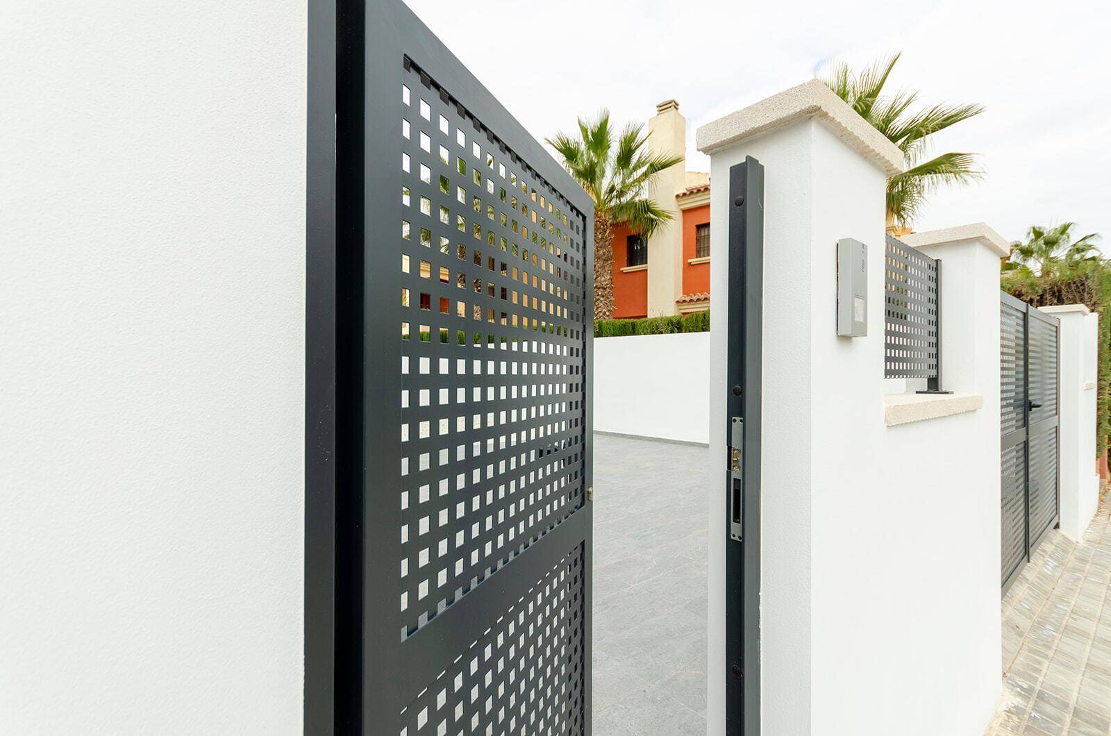 Modernes Eingangstor aus Metall mit quadratischem Muster und Gegensprechanlage.
